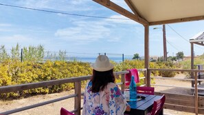 A person seated at a table with a view of a fence and vegetation. - Camping Felix de la Bastide (Saint-Mitre-les-Remparts)