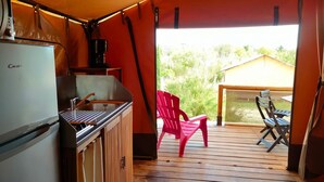 A compact kitchen with a refrigerator, sink, and coffee maker, leading to an outdoor deck with a table and chairs. - Camping Felix de la Bastide (Saint-Mitre-les-Remparts)
