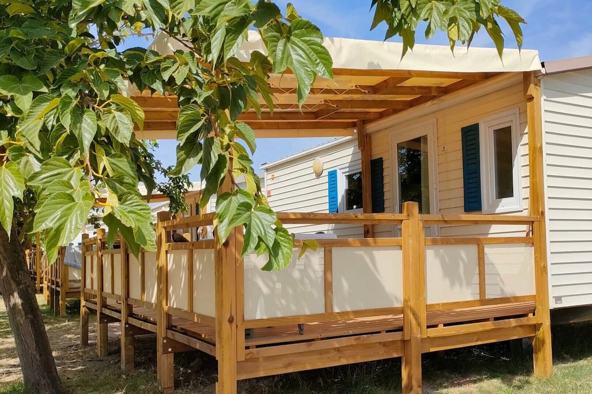 A mobile home with a wooden deck and a pergola.