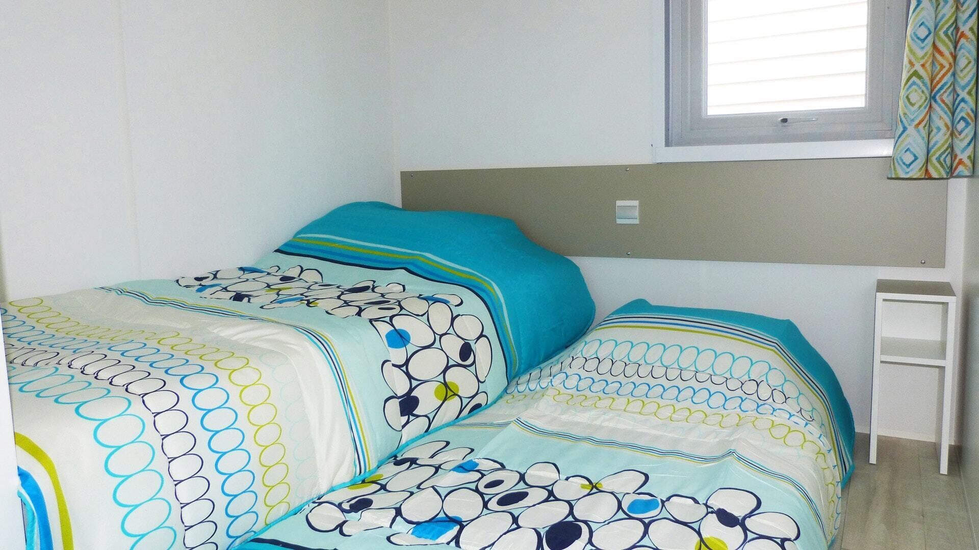 Une chambre à coucher comprenant un lit, une table de chevet, une fenêtre avec des stores et une étagère fixée au mur.