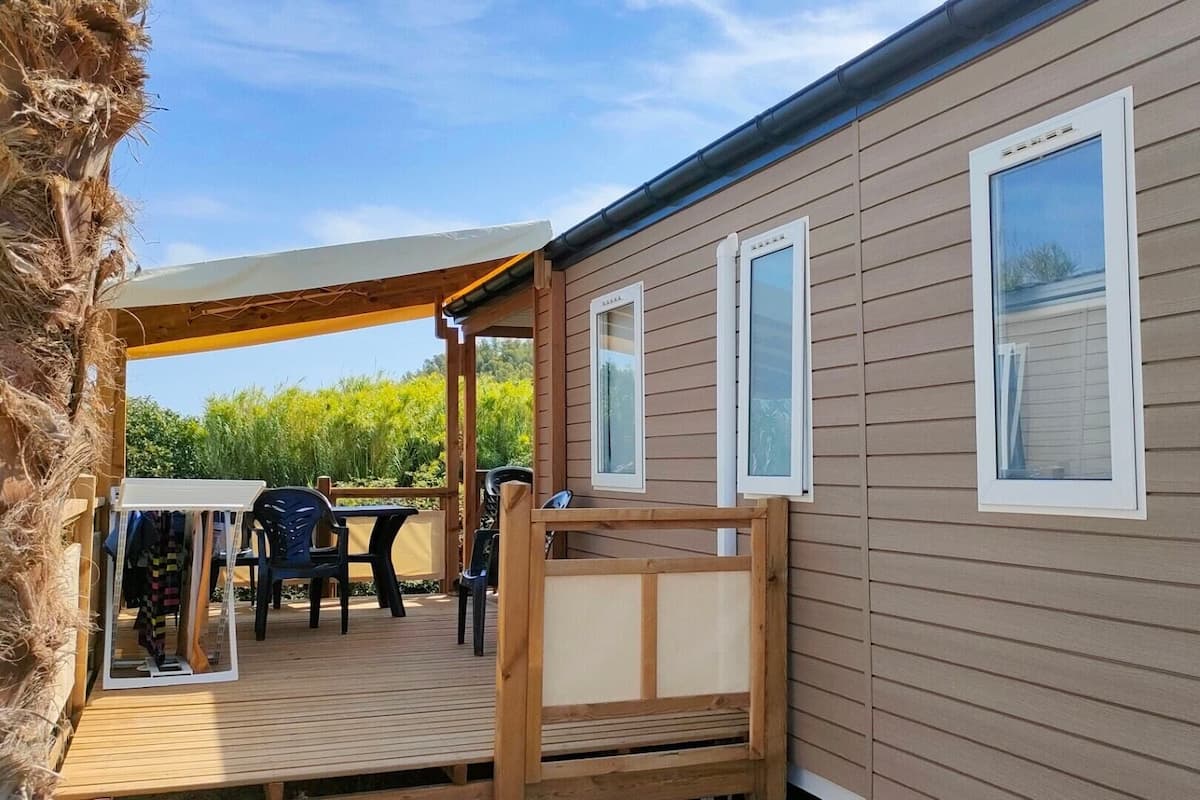A wooden deck with outdoor furniture, a covered area, and a window with blinds.