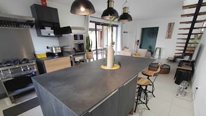 Une cuisine moderne dotée d’un îlot central, de tabourets de bar et de luminaires suspendus.