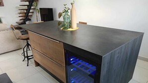 Une cuisine moderne dotée d’un réfrigérateur encastré, de tiroirs en bois et d’un tabouret de bar.