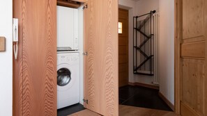 A laundry room with a washing machine and dryer, wooden doors, and a metal drying rack. - Italianway - Osteglio 15/F - Viola (Valdisotto)