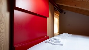 A hotel room with a red headboard, a neatly made bed with white linens, and a wooden ceiling. - Italianway - Osteglio 15/F - Viola (Valdisotto)