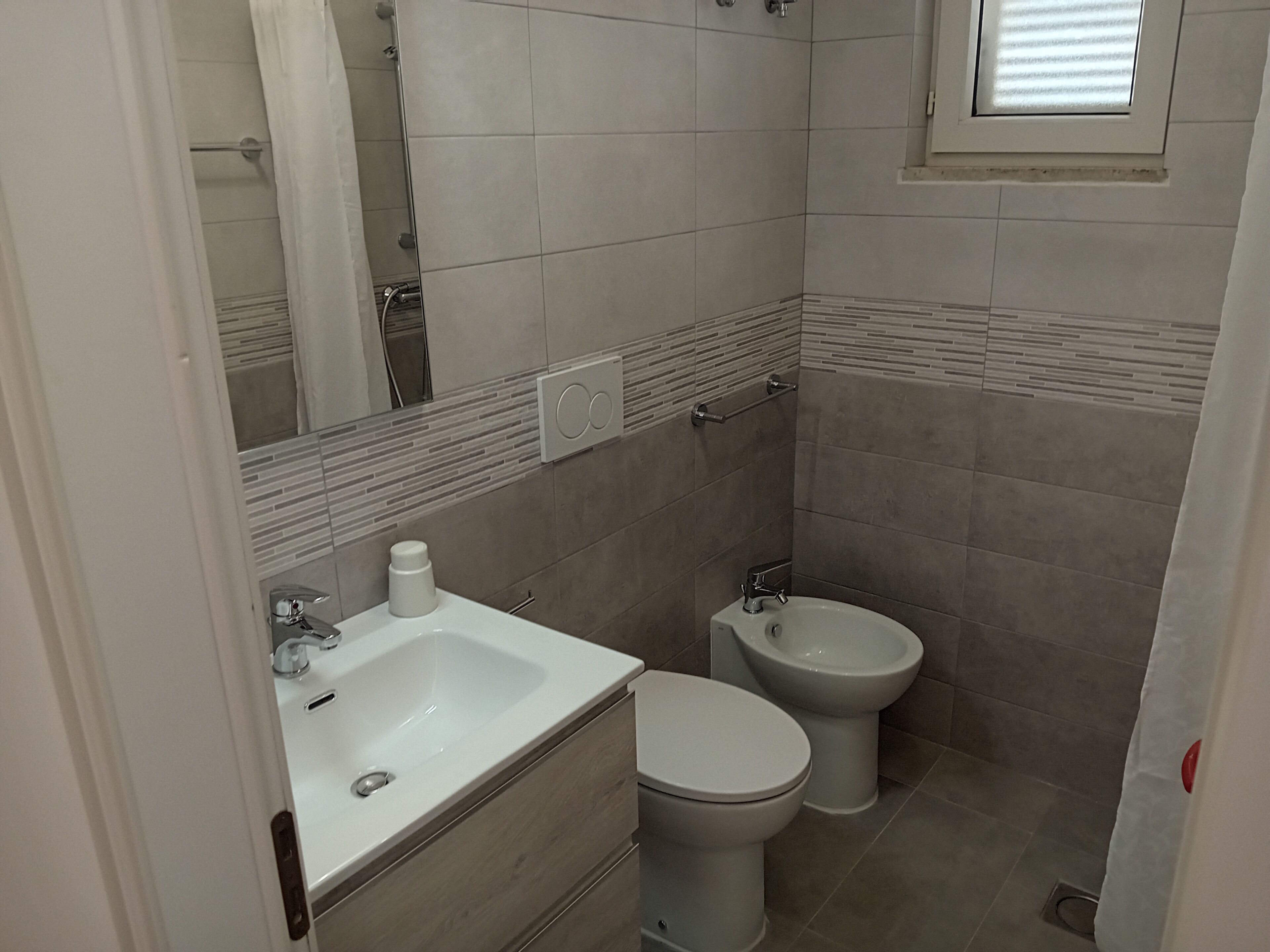 A bathroom with a sink, toilet, and bidet.