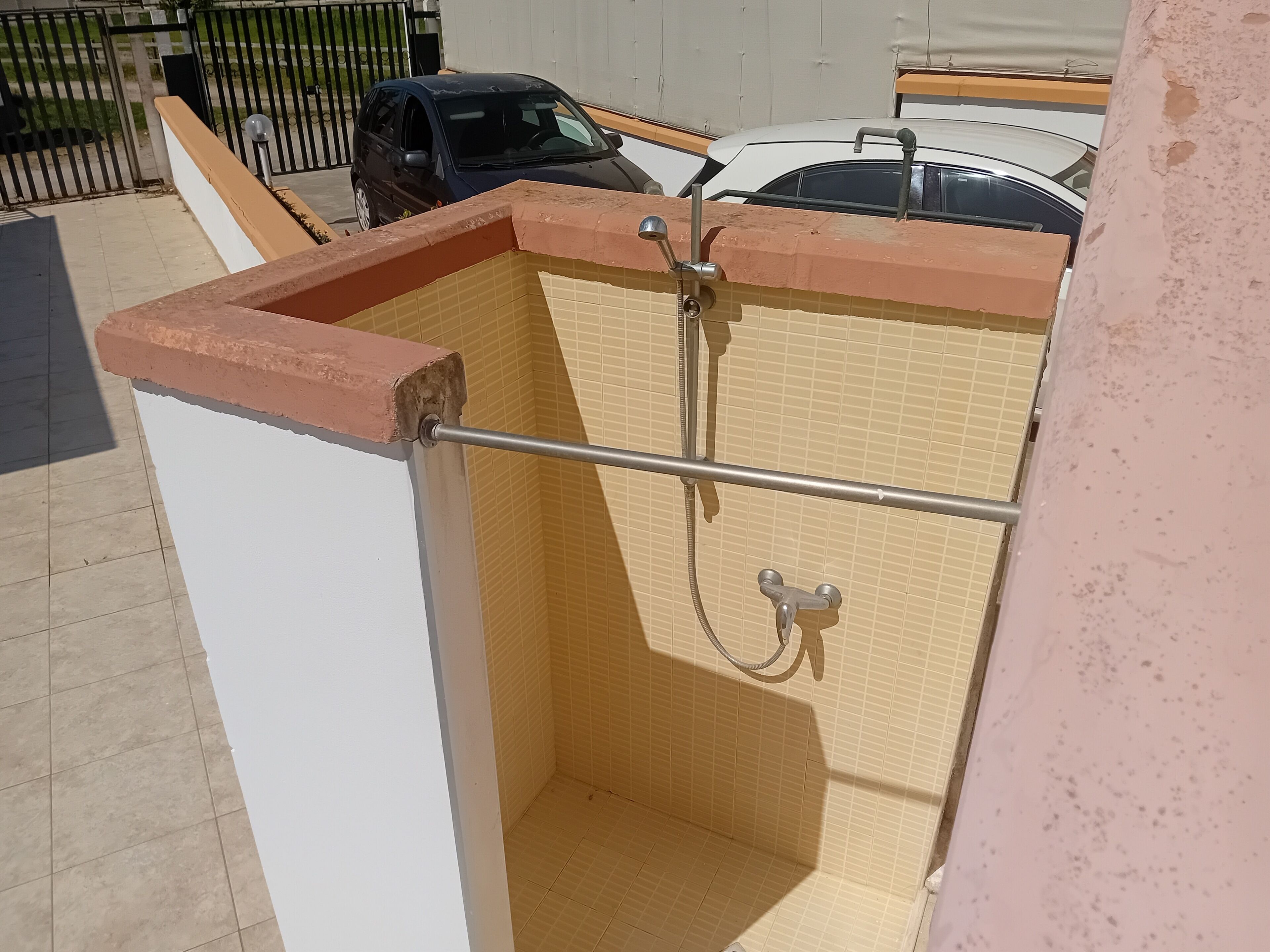 A small, enclosed shower area with tiled walls and a metal showerhead.