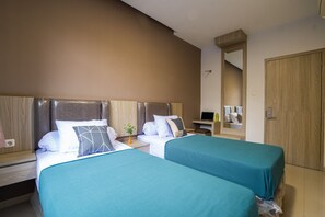 Une chambre d’hôtel avec deux lits, un bureau, un ordinateur portable et un miroir.