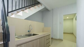 A kitchen with a sink, wooden cabinets, and a staircase.