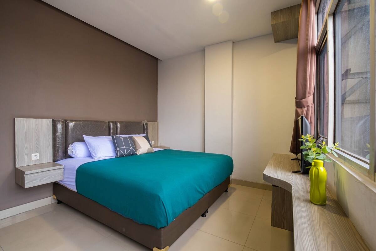 A modern bedroom with a bed, nightstand, and a window with curtains.