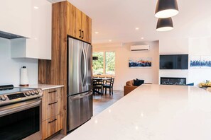 Une cuisine moderne dotée d’un réfrigérateur en acier inoxydable, de meubles en bois, d’un four encastré et d’un coin repas avec une table et des chaises.