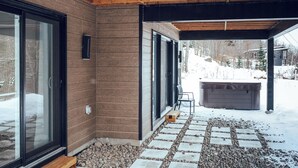 A covered outdoor area with a stone pathway leading to a hot tub. - Yéti de Tremblant - Spa & Forest Charm (La Conception)