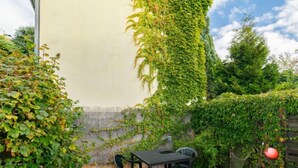 A patio with a table and chairs, surrounded by lush greenery and a stone wall. - Kornblume by Interhome (Zempin)