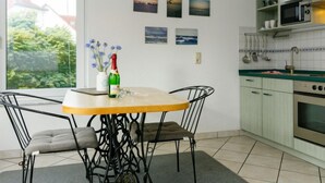 A modern kitchen with a dining area, featuring a table with chairs, a hanging light fixture, and a view of the outdoors through a window. - Kornblume by Interhome (Zempin)