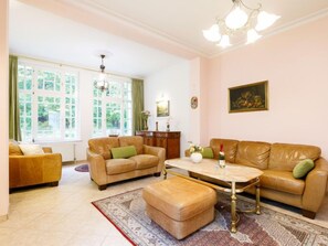 Ein großzügiges Wohnzimmer mit einem großen Fenster, einer Chandelier und einem Gemälde an der Wand.