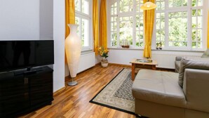 A living room with a TV, a large vase, a sofa, and a window with curtains. - Sonnenblume by Interhome (Zempin)