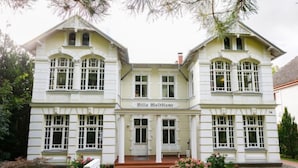 Un edificio a due piani con facciata simmetrica, ampie finestre e un ingresso centrale.