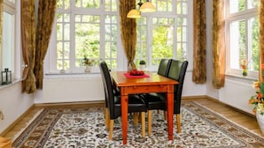 Una sala da pranzo con un tavolo in legno, sedie nere e un tappeto decorato.