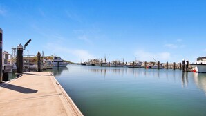 A marina with various boats docked, a concrete dock, and a clear blue sky.