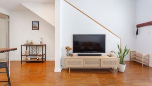 A living room with a flat-screen TV on a wooden console, a coffee table, and a potted plant.