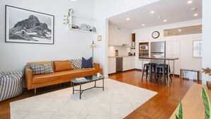 A modern living room with a sofa, coffee table, and a kitchen in the background.