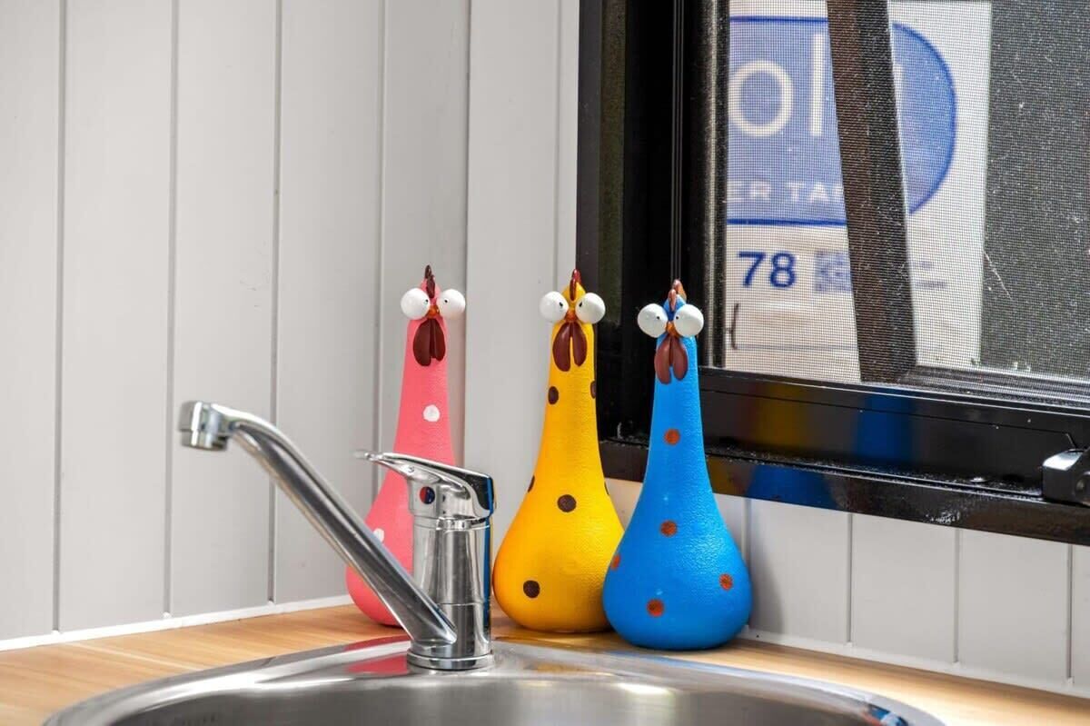 Een keukenkraan met drie vrolijk gekleurde, stippenprint zeephouders in dierenvormen.