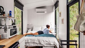 A compact bedroom with a bed, bedside table, and a window. - Clarence Farm Stay by Tiny Away (James Creek)