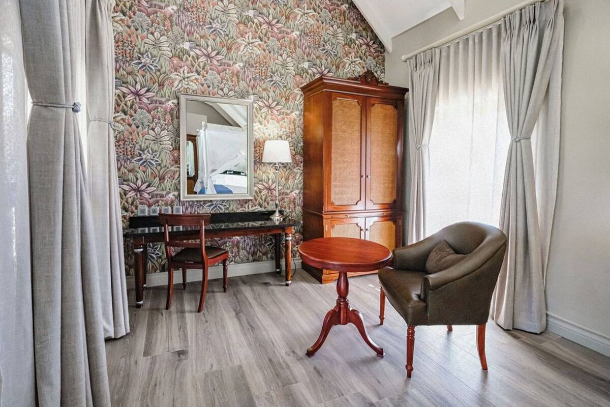 A room with a wooden cabinet, a round table, a chair, and a mirror on the wall.