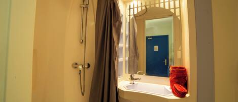 Une salle de bain avec une douche, un lavabo et un miroir.