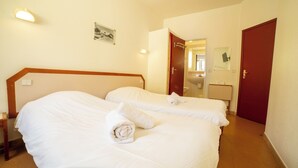 Habitación de hotel con dos camas, un baño y una puerta.