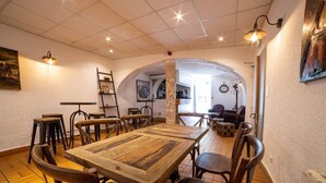 Un comedor con una gran mesa de madera, varias sillas y una zona de bar con taburetes.
