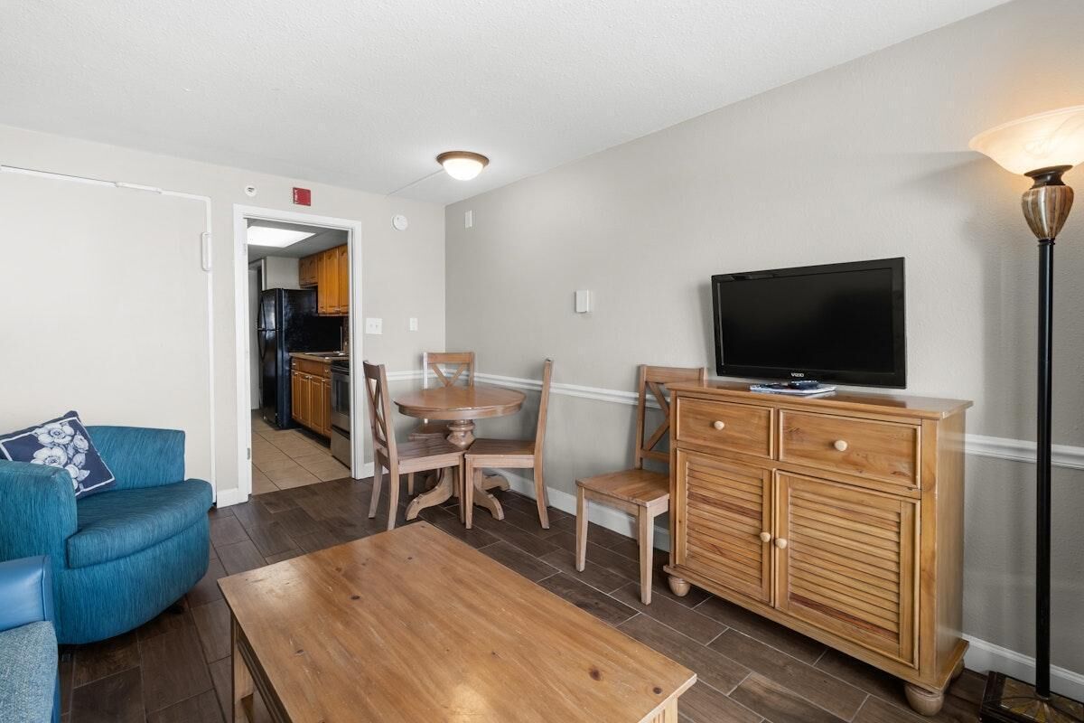 A living room with a blue sofa, wooden coffee table, and a TV on a wooden cabinet.
