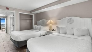 A hotel room with two beds, a nightstand with a lamp, and a view of the balcony. - Spacious Oceanfront Ste with Breakfast 7th Flr (Myrtle Beach)