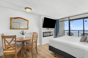 A hotel room with a bed, a dining table with chairs, a television, and a balcony with a view. - Astonishing Oceanfront Suite: 7th Flr W Breakfast (Myrtle Beach)