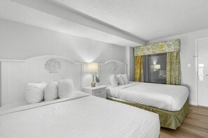 A hotel room with two beds, a nightstand with a lamp, a decorative wall piece, and a window with curtains. - Astonishing Oceanfront Suite: 7th Flr W Breakfast (Myrtle Beach)