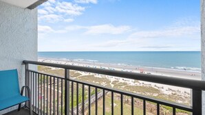 A balcony with a view of the beach and ocean.