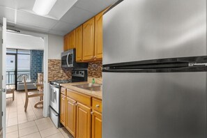 A modern kitchen with stainless steel appliances, wooden cabinets, and a view to the outside. - Majestic Oceanfront Ste: Includes Breakfast (Myrtle Beach)
