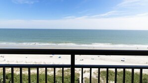 A beach view from a balcony with a railing, sandy beach, and ocean. - Awe Inspiring Oceanfront Suite w/Breakfast 8th Flr (Myrtle Beach)