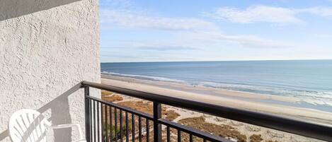Ein Balkon mit Blick auf Strand und Meer.