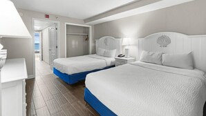 Habitación de hotel con dos camas, un escritorio y vista al océano.