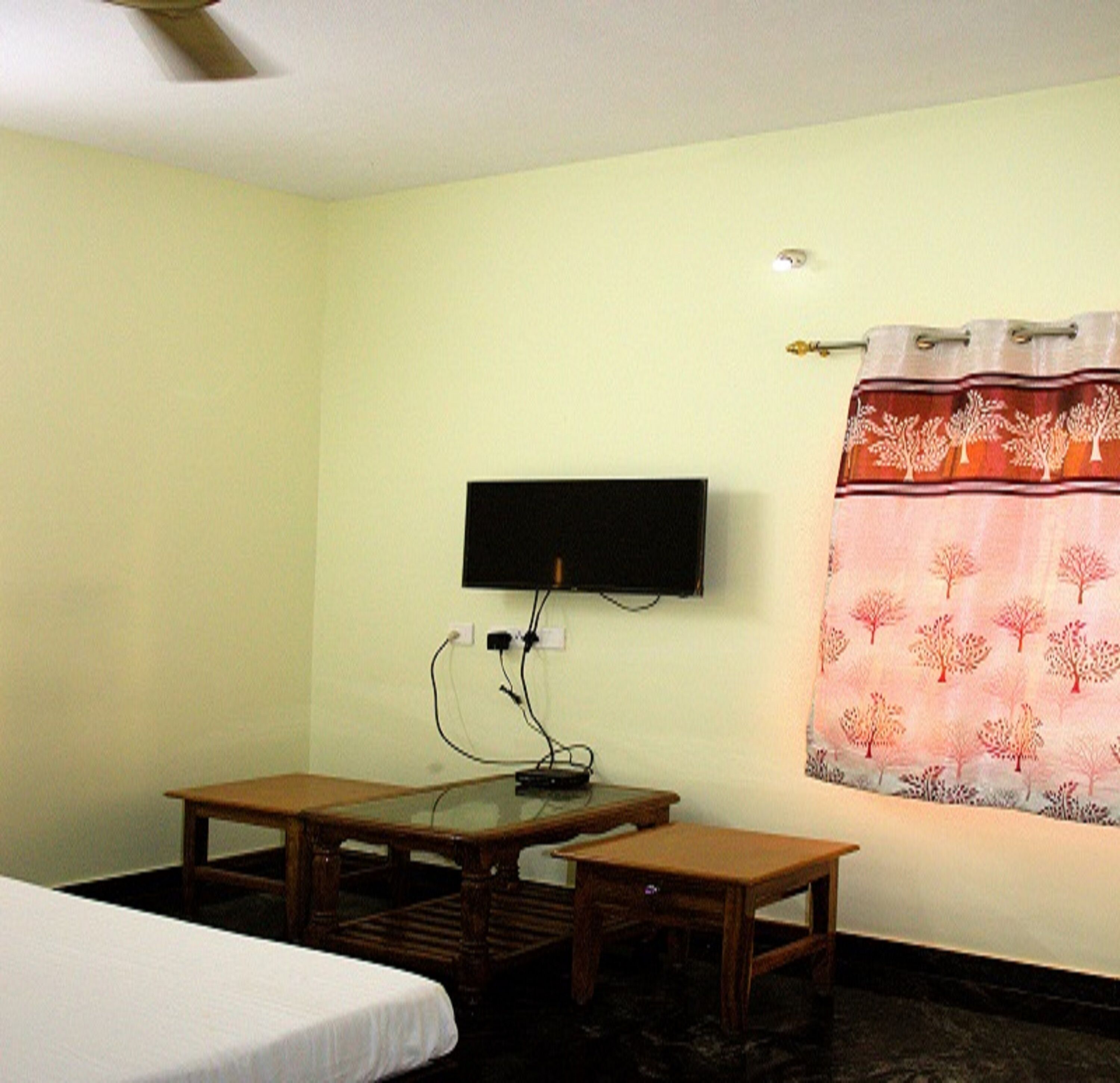 A room with a bed, a desk, and a television mounted on the wall.