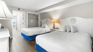 Una habitación de hotel con dos camas, un escritorio, una lámpara y un armario.