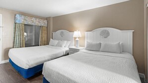 A hotel room with two beds, beige walls, and a window with curtains. - Mesmerizing Oceanfront Ste 9th Flr Free Breakfast (Myrtle Beach)