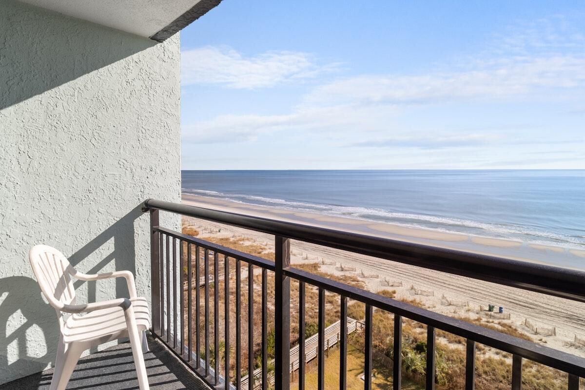 A balcony with a view of the beach and ocean.