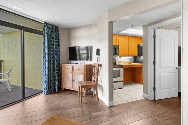 Een modern appartement met een keuken, eethoek en een schuifpui naar een balkon.