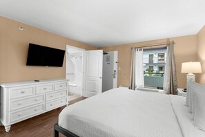 A hotel room with a bed, a dresser, a television, and a balcony view.