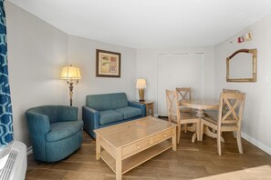 Un saló amb un sofà blau, una taula de centre de fusta i una taula de dinar amb cadires.