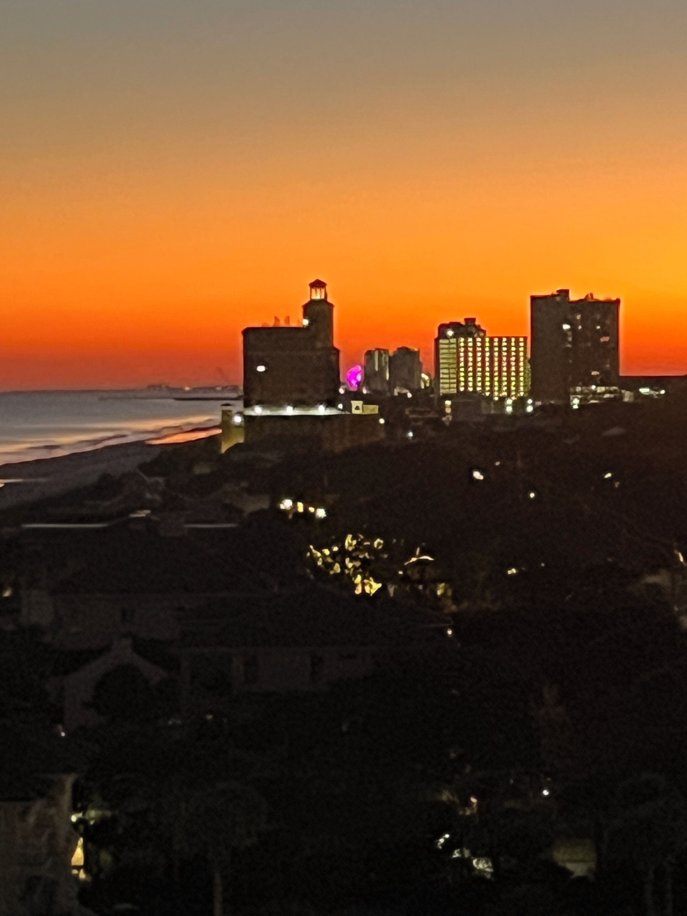 A city skyline at sunset with buildings silhouetted against a vibrant sky.