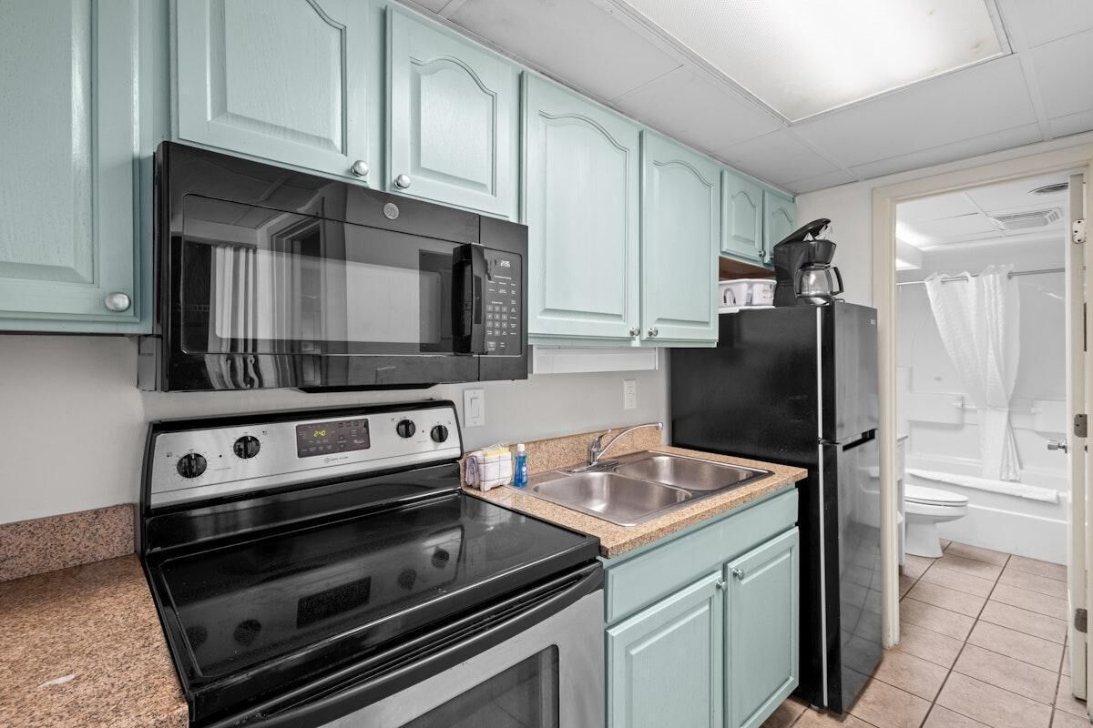 A kitchen with a microwave, stove, sink, and refrigerator.