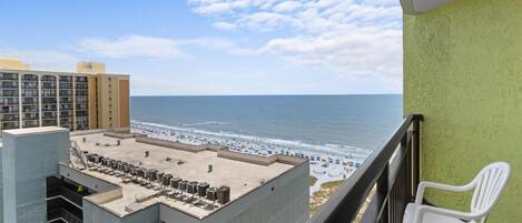 A balcony with a view of the beach and ocean.